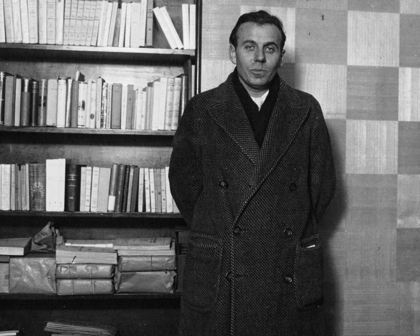 Imagen de Louis-Ferdinand Céline, de pie junto a un librero.